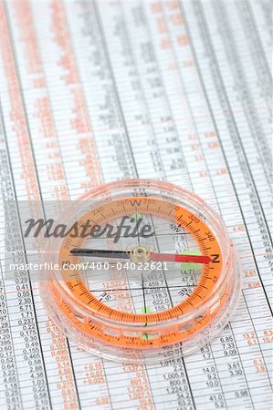 Close up of compass on stock market numbers