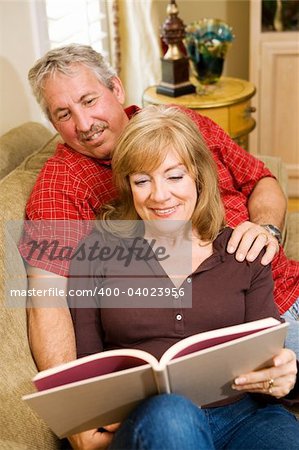 Attractive retired couple at home reading together.