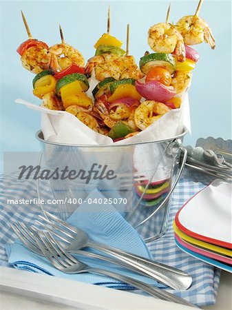 Shrimp kebabs with colorful bell peppers, red onions, and tomatoes, displayed in a metal bucket.