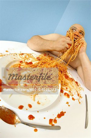 An overweight man enjoying a plate of spaghetti.  Shot with fish-eye lens.  Focus is on the face.