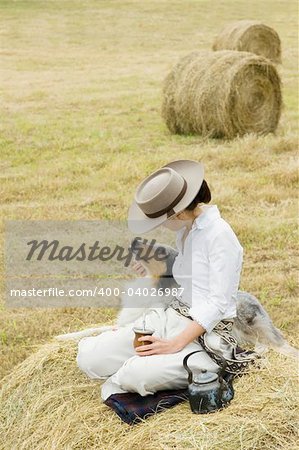 A young Argentinean farm girl and her dog share a moment while relaxing in a field.