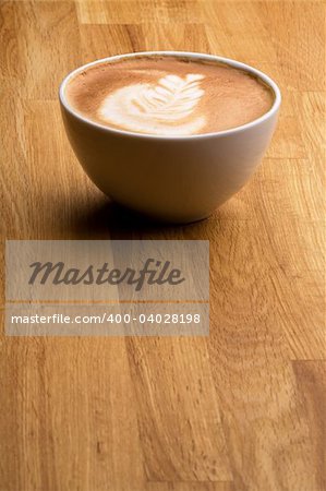 A cappuccino with latte art on a wooden table