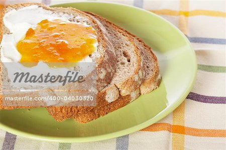 Toast with butter and peach jam in the green plate with soft shadow on square mat background. Shallow depth of field