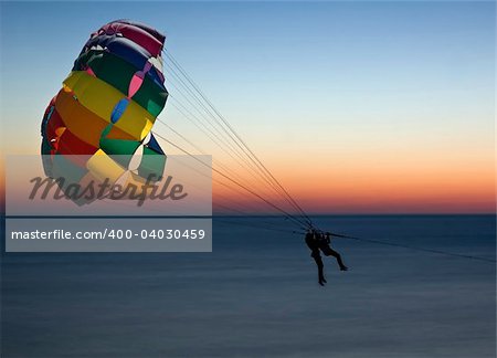 Two women parasailing against a dawn sky