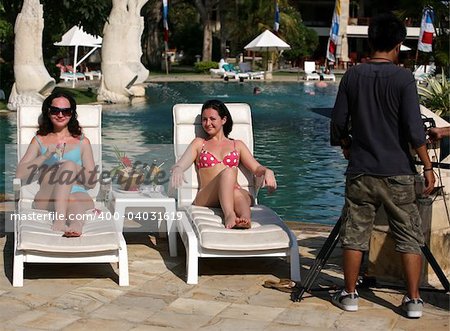 Two young girls with cocktails near the swimming pool