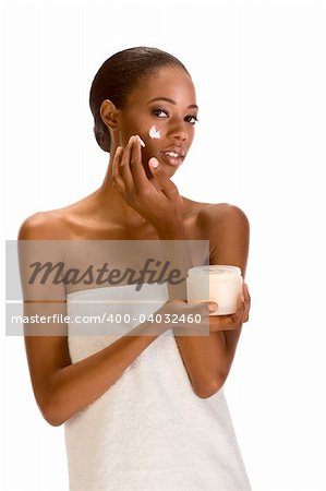 Beautiful young ethnic woman with Slicked Back Hair wrapped in white bath towel applying moisturizer on her face