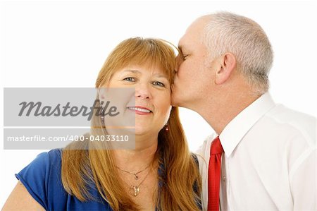 Beautiful mature woman receiving a kiss on the cheek from her husband.  Isolated on white.