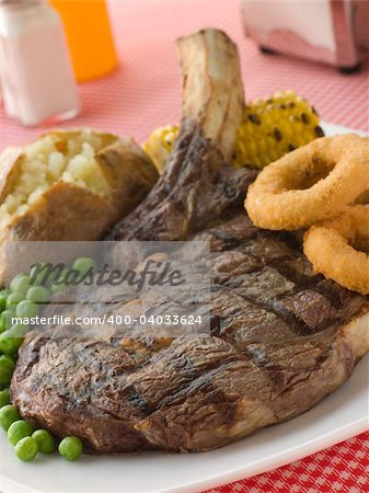 Ribeye Steak on the bone with Baked Potato Peas Onion Rings and