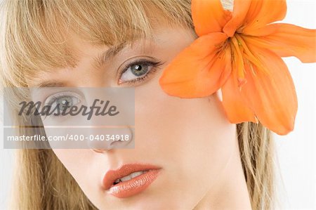 nice clode up of a young pretty woman with an orange lily between hair