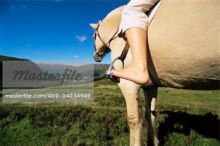 Young woman riding horse in rural setting