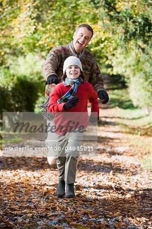 Grandfather and grandson running through autumn woods