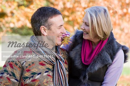 Senior couple on autumn walk with trees in background