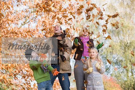 Father throwing autumn leaves in the air