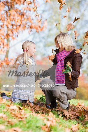 Mother and daughter throwing autumn leaves in the air