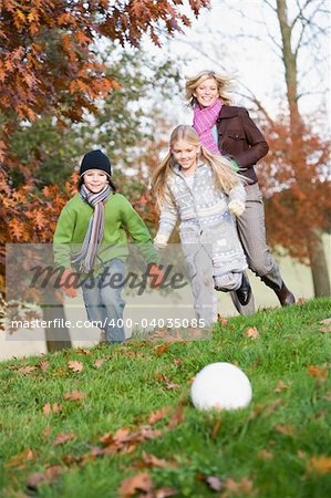 Mother and children playing football in autumn garden