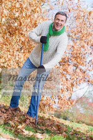 Senior man tidying autumn leaves in garden