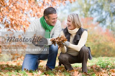 Senior couple collecting autumn leaves together