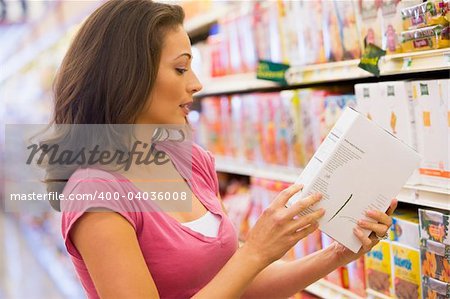 Woman checking food labelling in supermarket