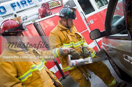 Firefighters cutting open a car to help an injured person