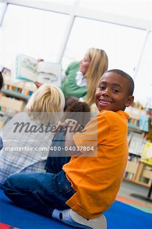 Kindergarten teacher reading to children in library, boy looking