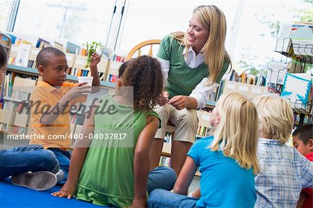 Kindergarten teacher and children looking at seedling in library