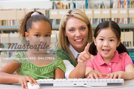 Kindergarten teacher sitting with children at computer