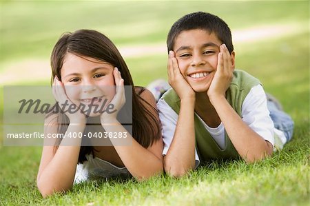 Two children relaxing in park looking to camera