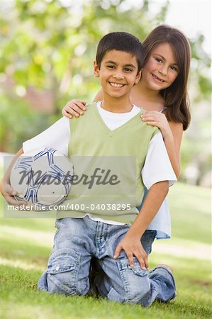 Two children playing in park together looking to camera