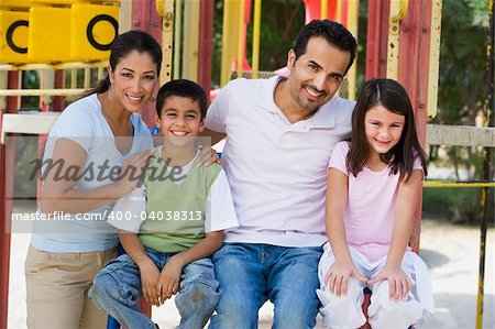 Family having fun in playground on climbing frame