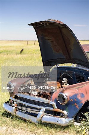 abandoned vintage car with popped hood in a field