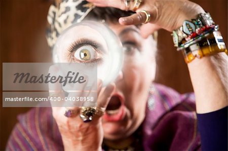 Female gypsy fortune teller holding a crystal ball to her eye