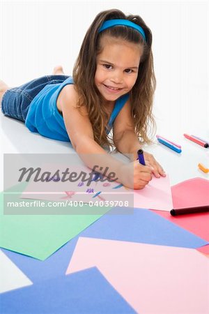 Young latino girl coloring on construction paper and smiling.