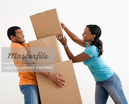 African American woman placing boxes on large stack man is holding.