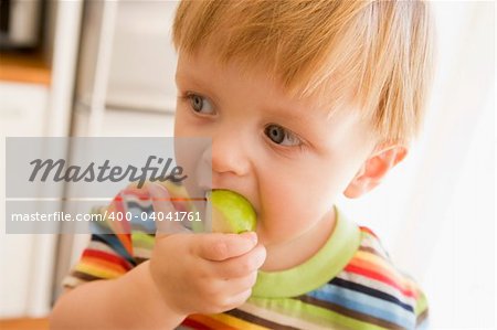 Young boy eating apple indoors