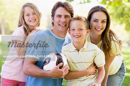 Family standing outdoors holding volleyball smiling