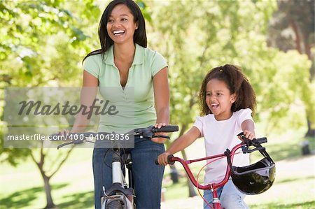 Woman and young girl on bikes outdoors smiling