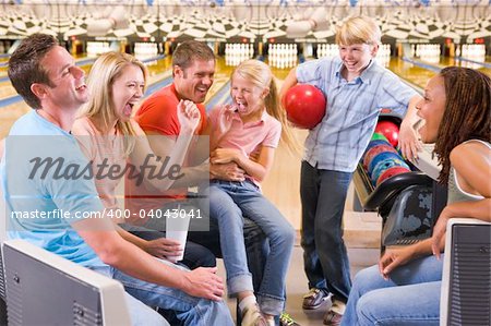 Family in bowling alley with two friends cheering and smiling