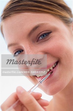 Woman with lipgloss applicator smiling