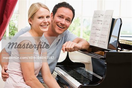 Couple sitting at piano smiling