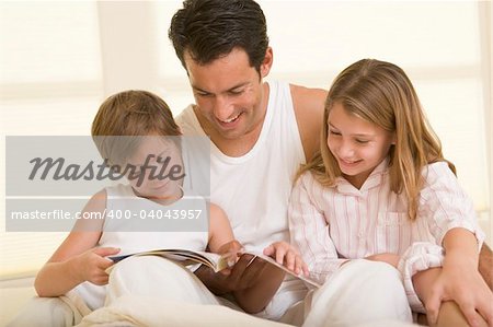Man with two young children sitting in bed reading a book and sm