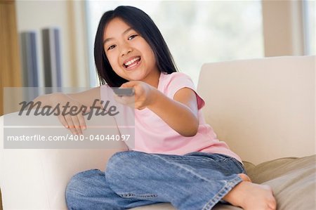 Young girl in living room with remote control smiling