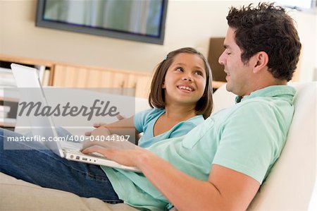 Man with young girl in living room with laptop smiling