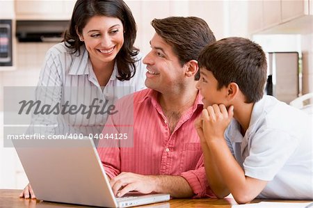 Family in kitchen with laptop smiling