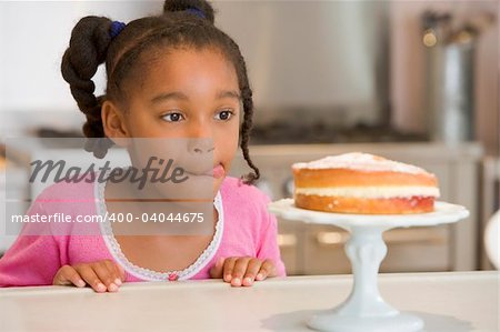 Girl staring longingly at cake at home licking lips