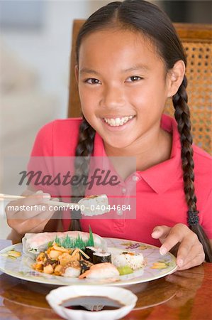 Young girl in dining room eating Chinese food smiling