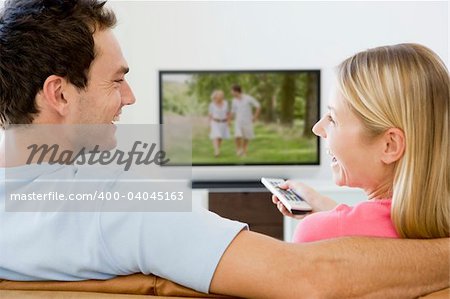 Couple in living room watching television smiling