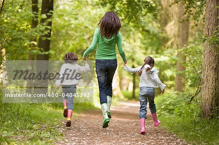 Mother and daughters skipping on path smiling