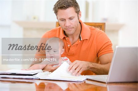 Father and baby in dining room with laptop