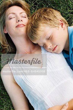 Mother and son lying outdoors sleeping