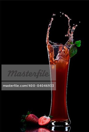 View of strawberry juice splashing out of glass on black back